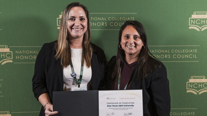 Two women standing together holding a certificate of completion.