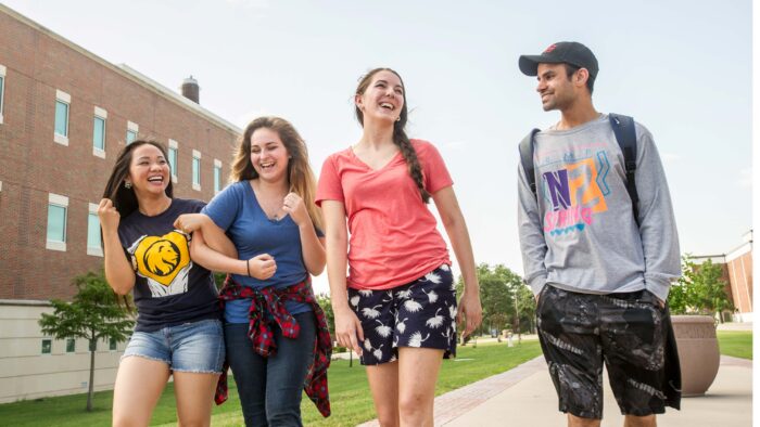 Four students walking outside beside a building.