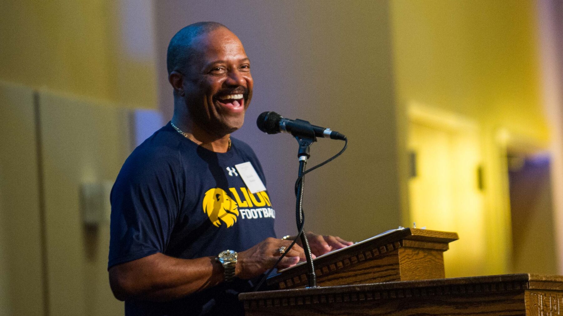 Man smiling while standing at a podium.
