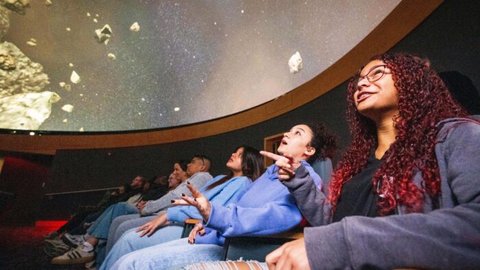 Students leans back in the planetarium to watch a planetary movie on the dome above