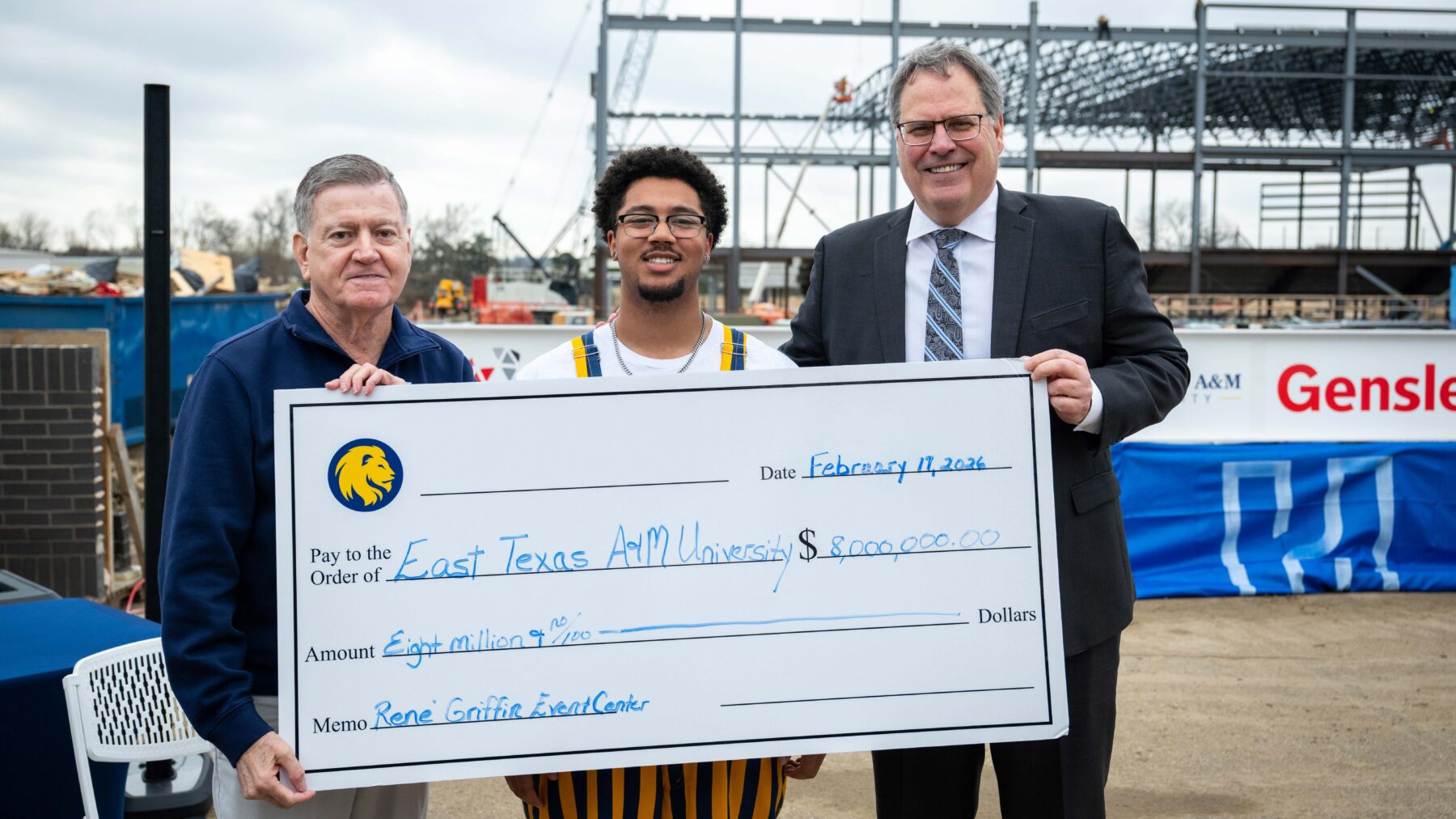 Rene' Griffin, a student and President Mark Rudin hold an oversized check in front of them that is filled out for 8 million dollars.