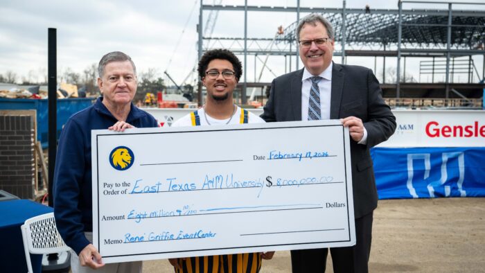 Rene' Griffin, a student and President Mark Rudin hold an oversized check in front of them that is filled out for 8 million dollars.