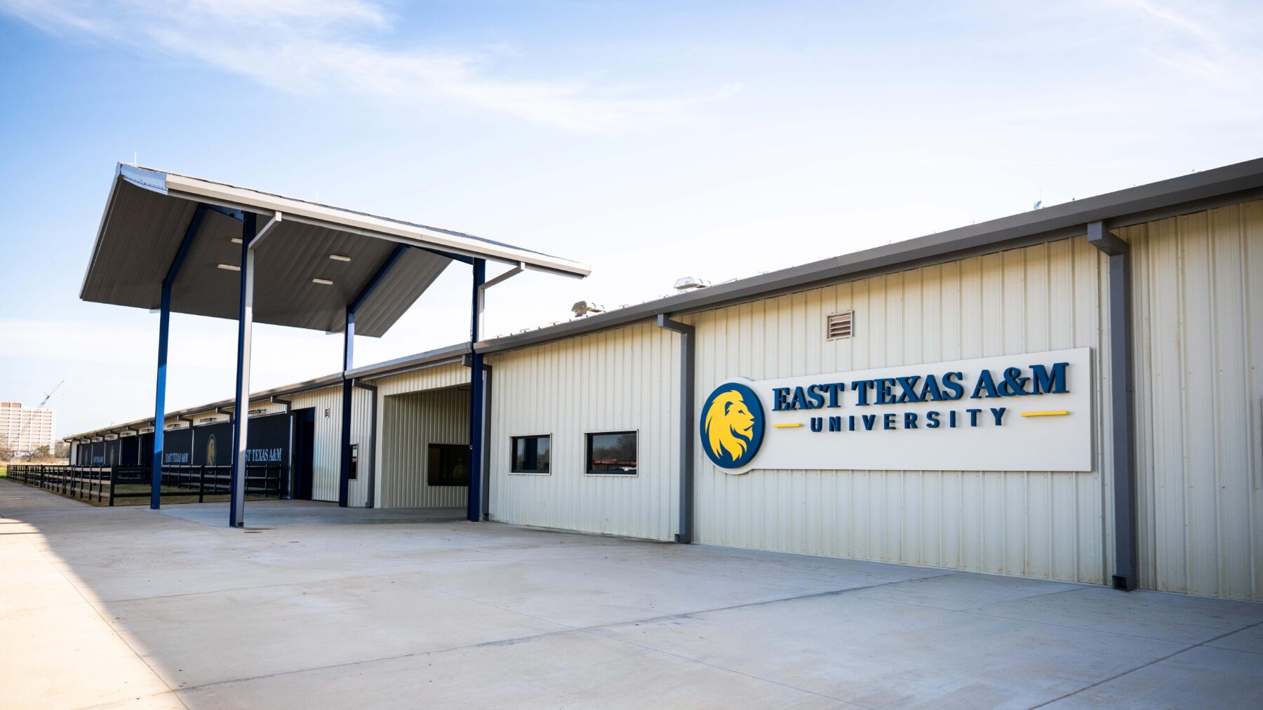 A white metal building with a metal awning in front with the words "East Texas A&M Univeristy" printed on the front of the building.