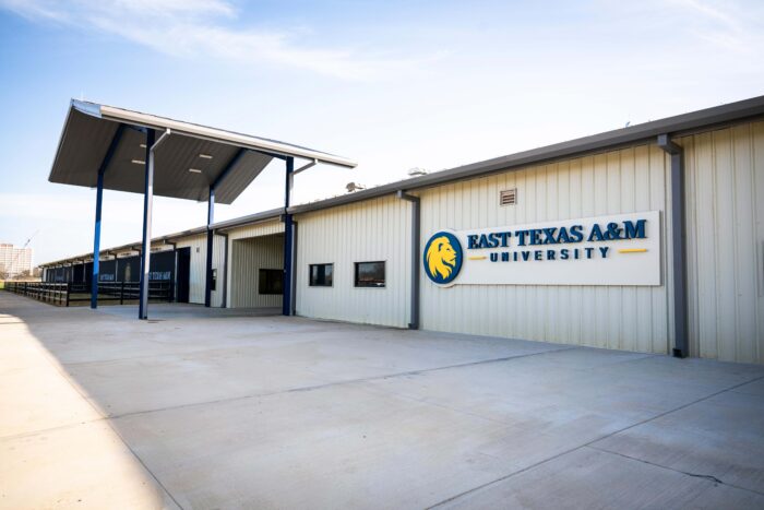 A white metal building with a metal awning in front with the words "East Texas A&M Univeristy" printed on the front of the building.