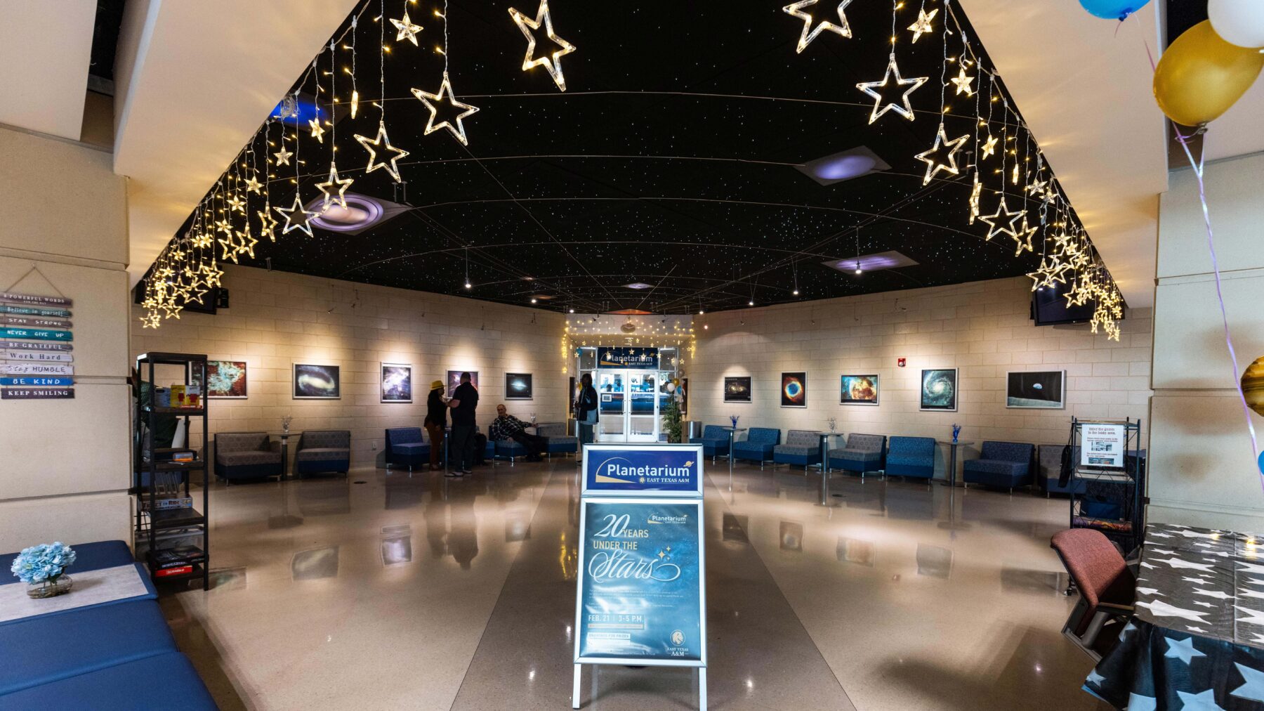 A lobby area, with bright stars hanging from the ceiling and pictures of space around the walls.