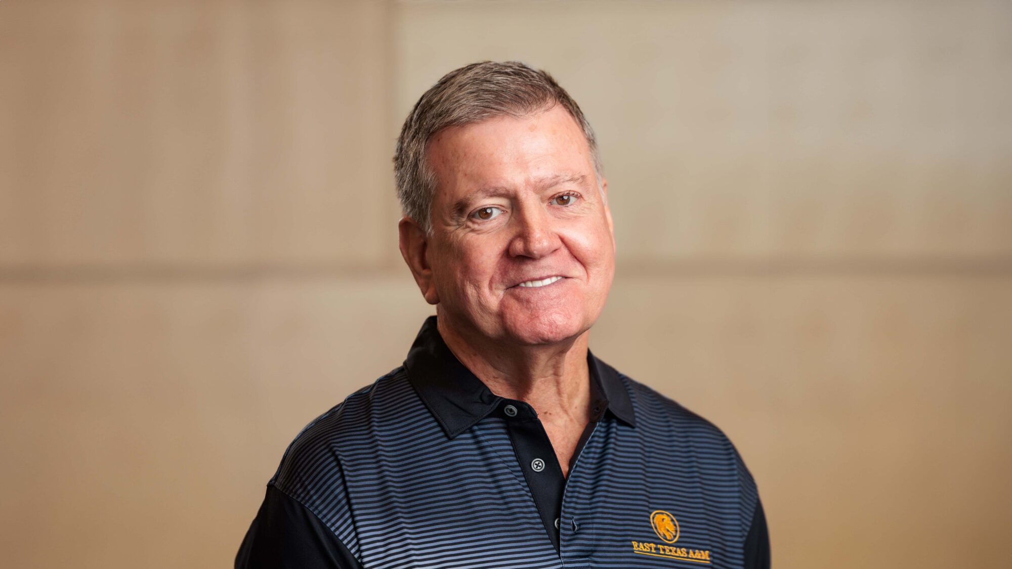 A person smiles for the camera, wearing a blue polo-style shirt.
