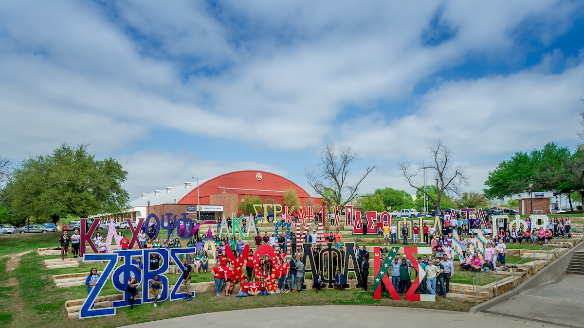 Students holding giant Greek letters on campus