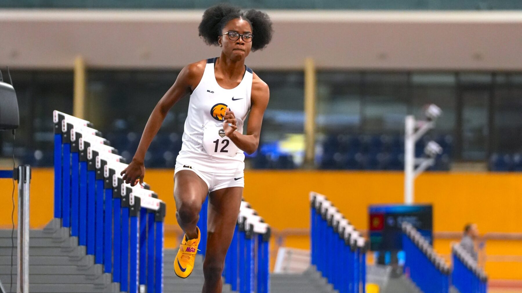 A high jumper approaches the bars during a track and field meet.