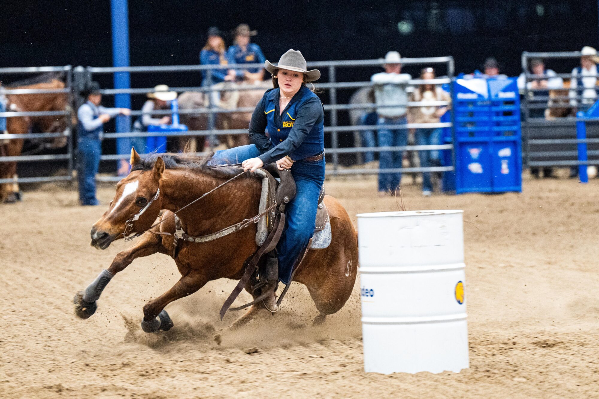 A barrel racer turns their horse sharply around a barrel during a rodeo event.