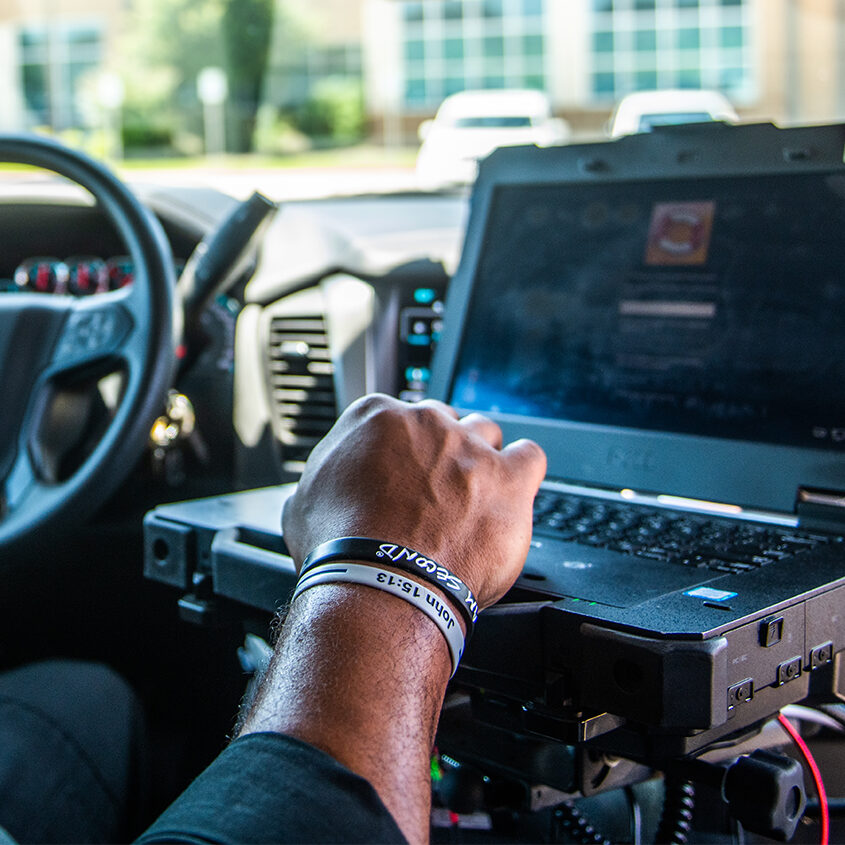 Police officer inside police car looking at the computer.