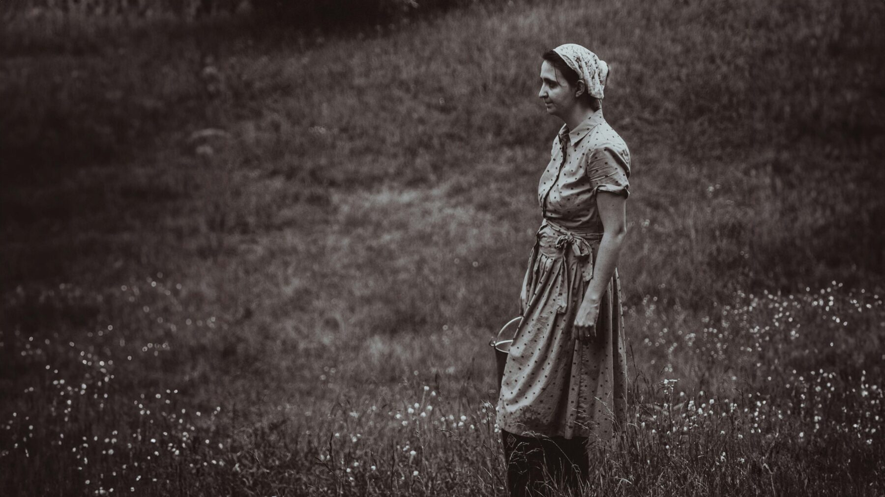 Photo for decorative use. Black and white side profile of a women in a dress holding a milk pail.
