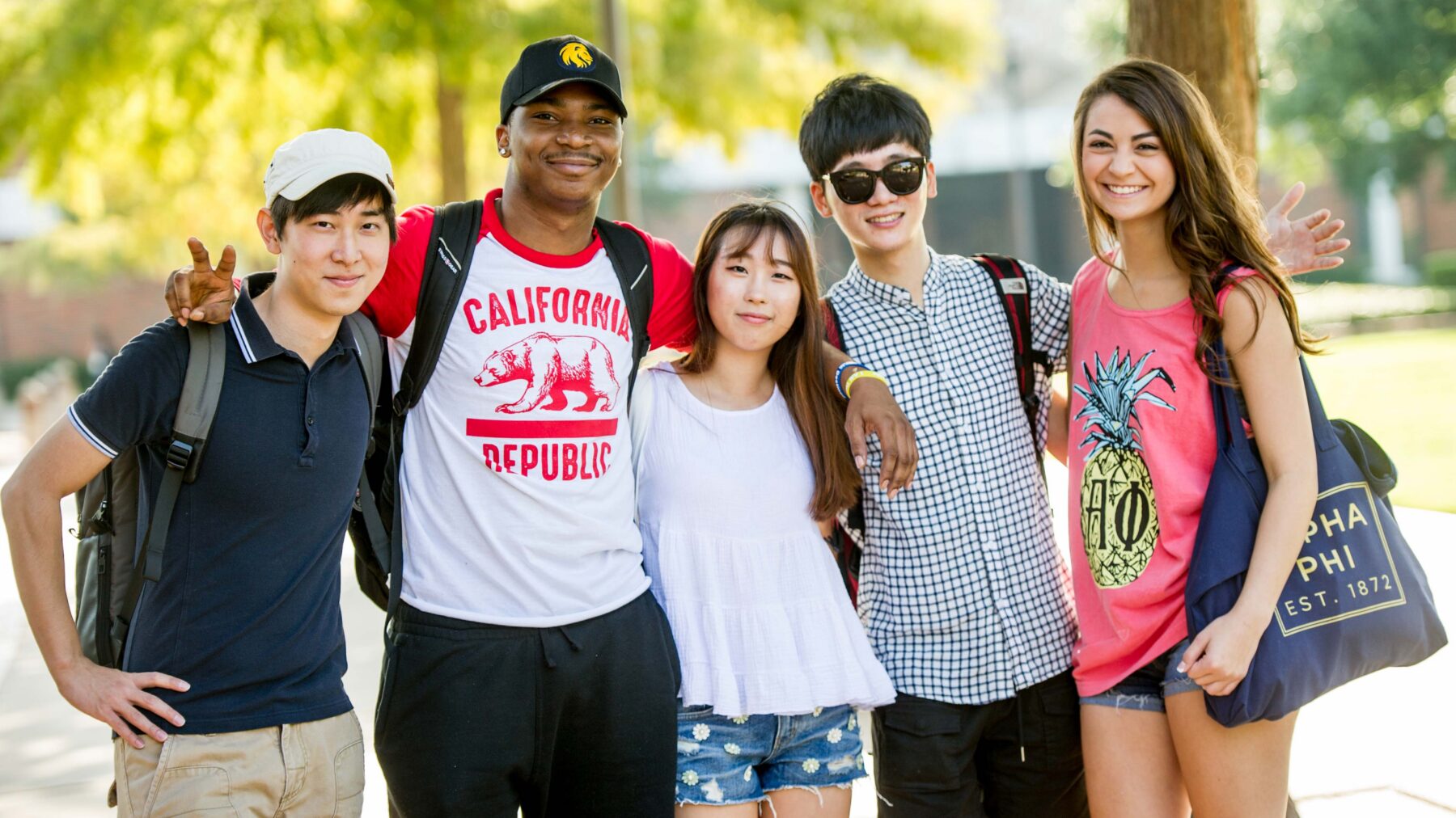 Young people standing outside smiling in the sunshine.