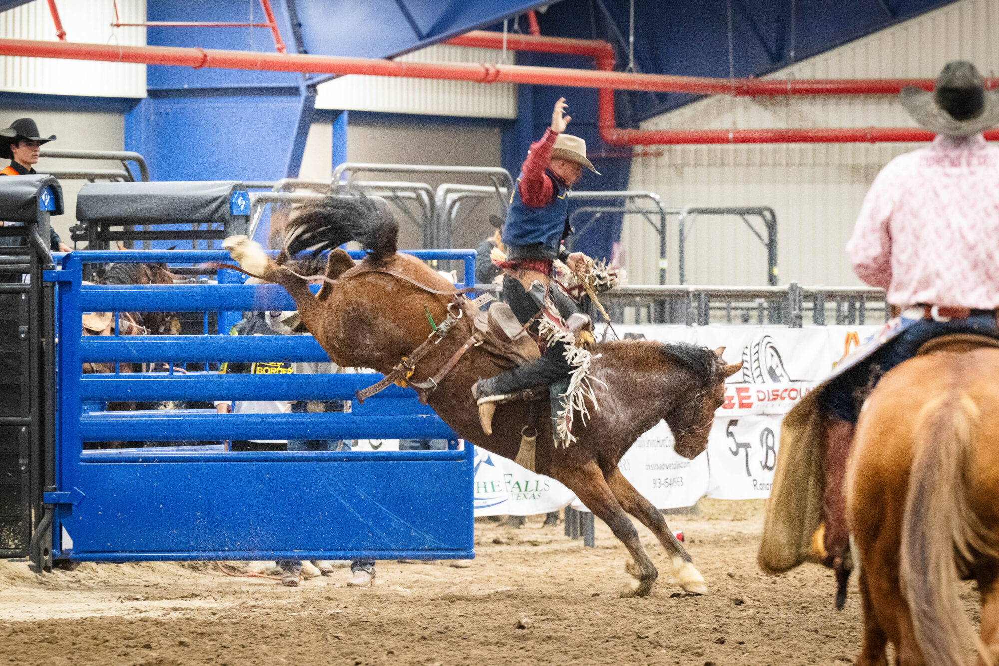 A cowboy rides a bucking horse during a rodeo competition.