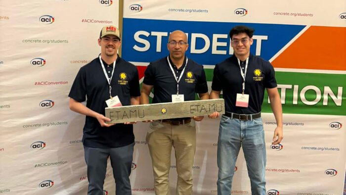 Three men standing and holding a piece of concrete.