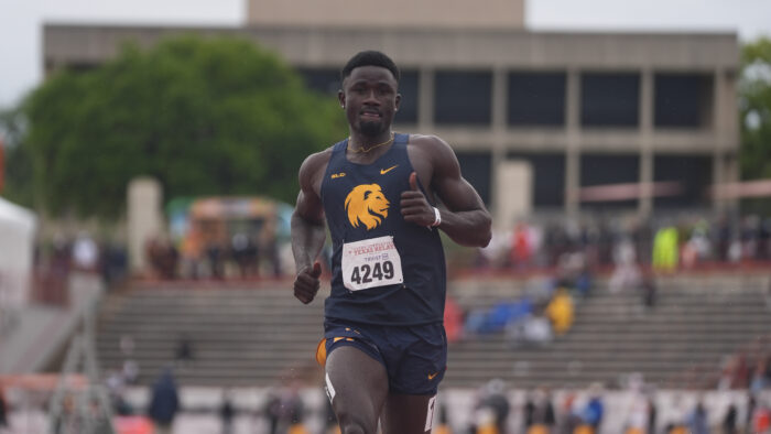 A track runner sprinting toward the camera on a running track.
