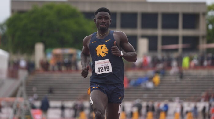 A track runner sprinting toward the camera on a running track.