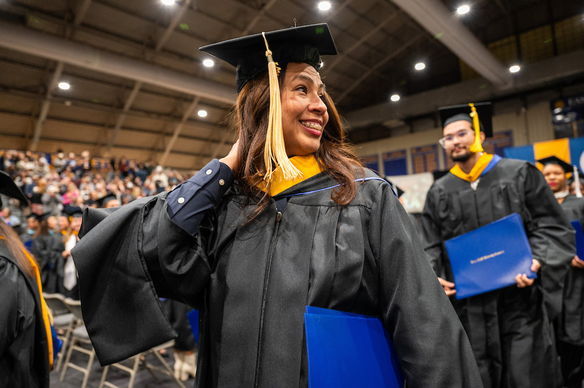 Female graduate looks over her shoulder as she exits graduation with her diploma