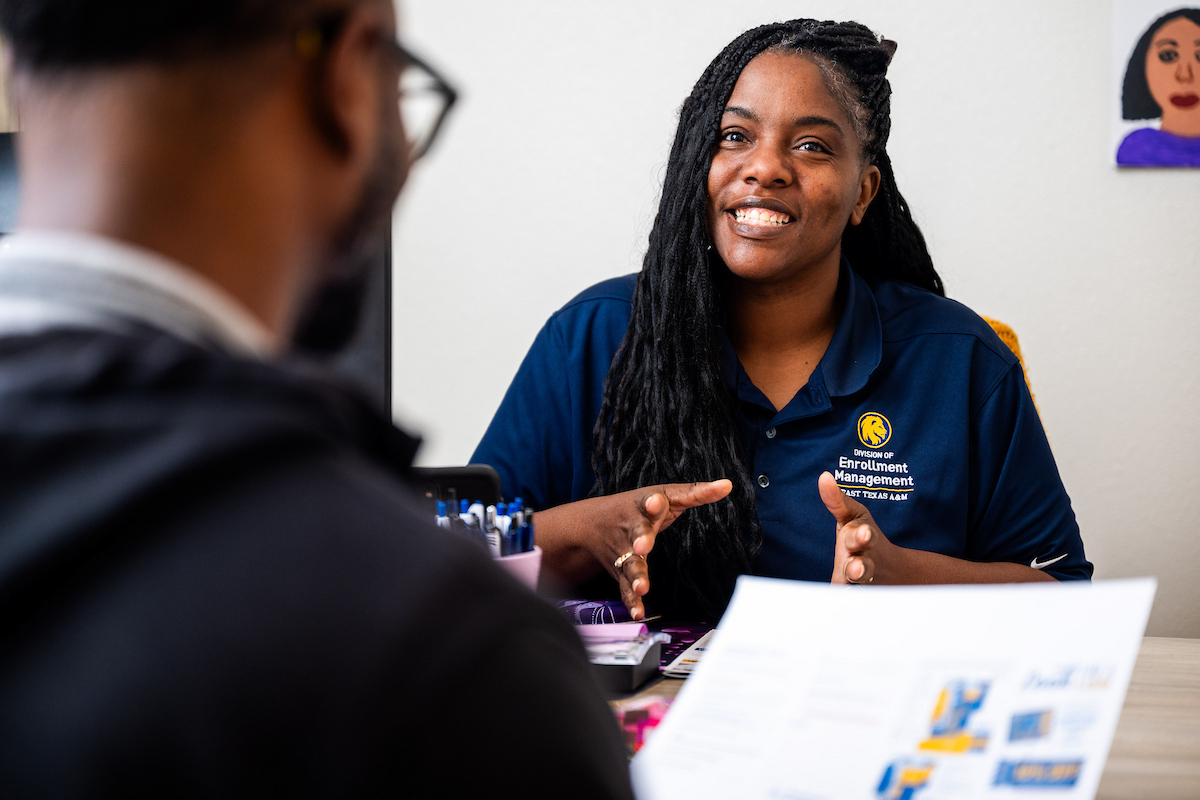 Enrollment specialist sitting at her desk helping a student with paperwork