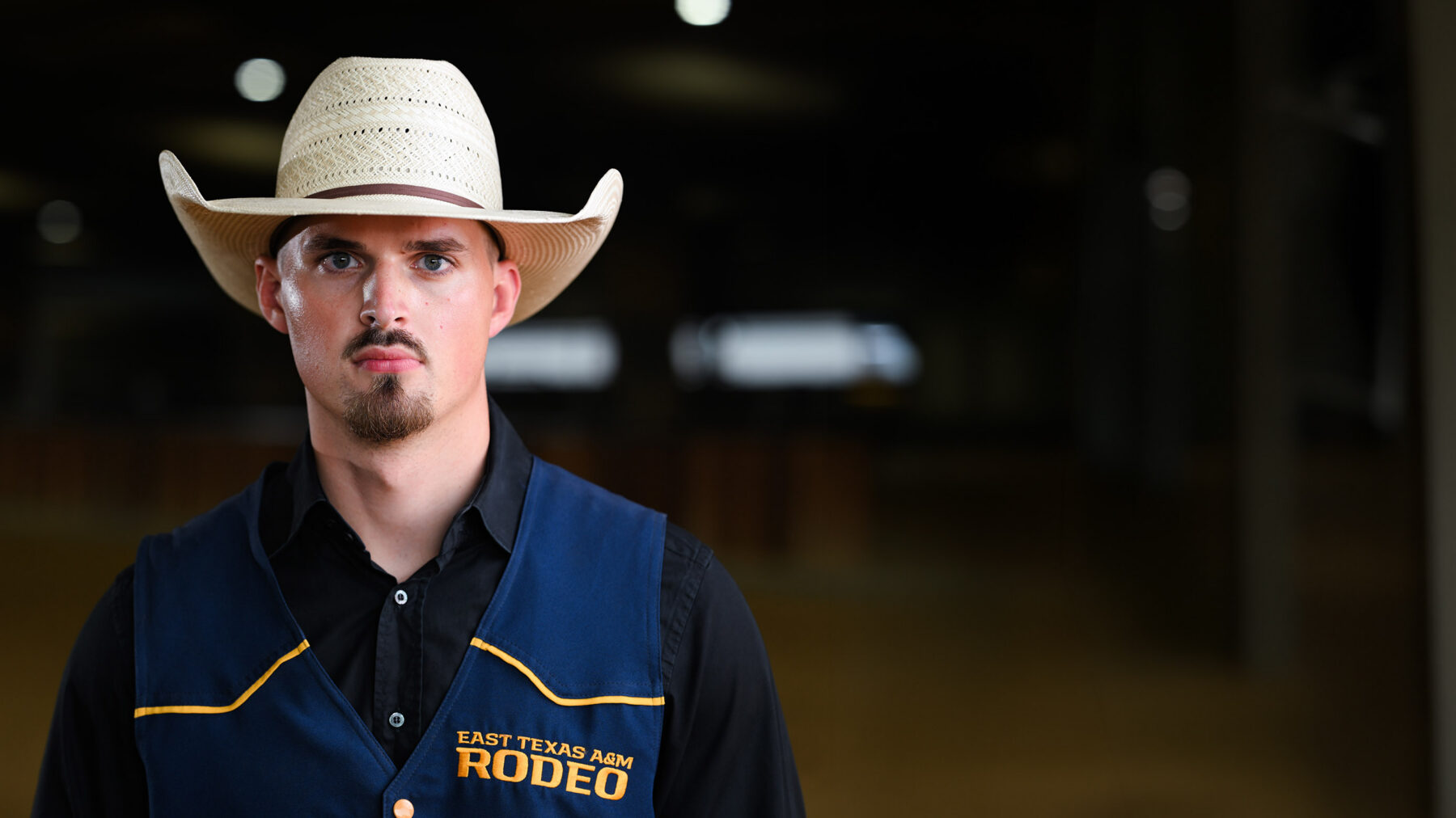 A person in vest and cowboy hat staring into the camera.