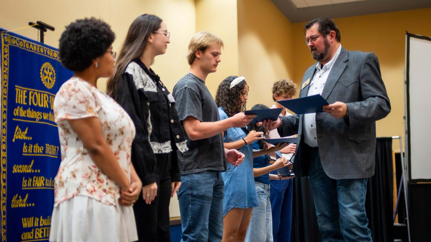 A man handing out awards to students on a stage.