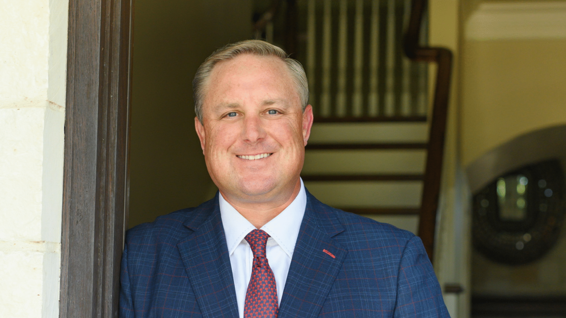 A headshot photo of a person in a suit.