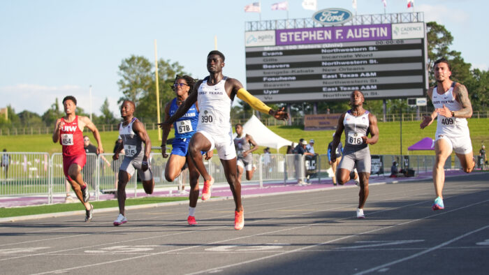 A group of track athletes running in a 100 meter dash competition.