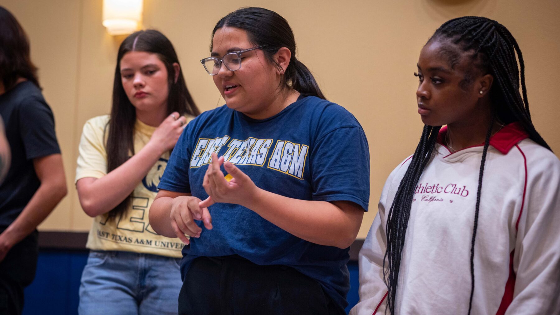 Three young women standing in a row talking.