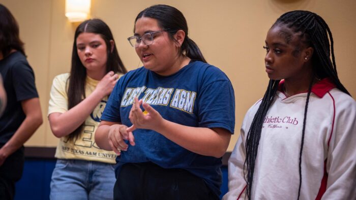 Three young women standing in a row talking.
