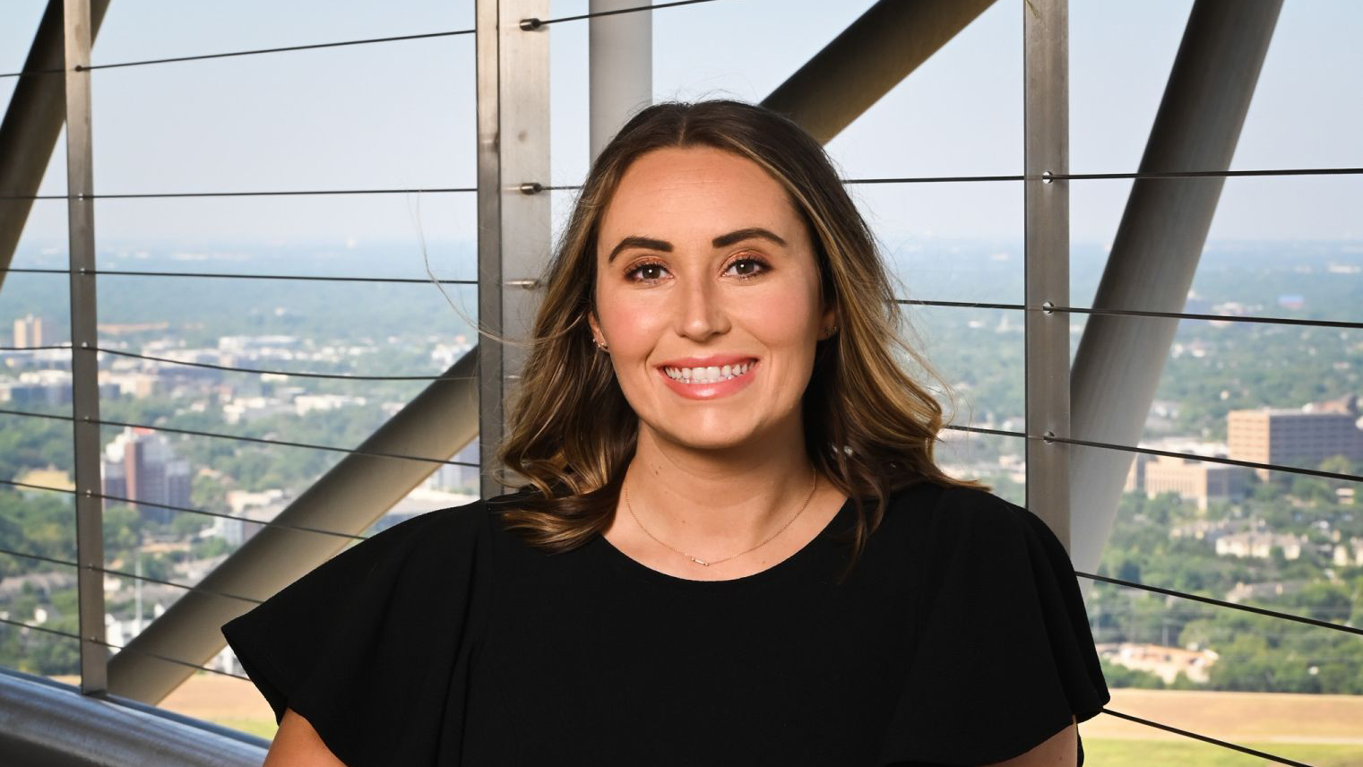 A headshot photo of a person taken from inside of a high rise building