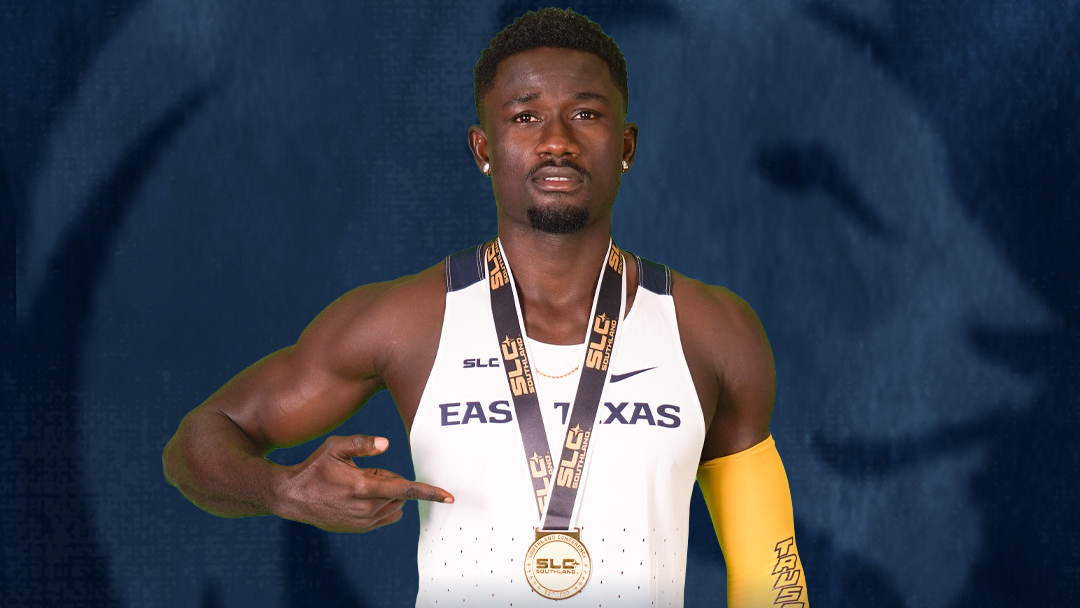 A track and field runner posing with a gold medal