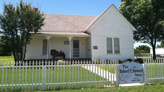 A old white house with a white fence in front of it.