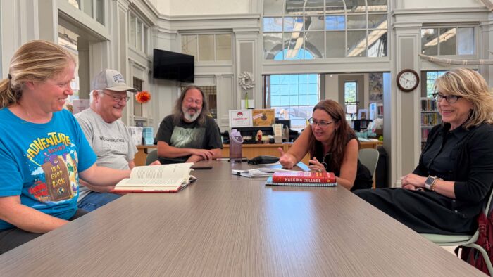 Five people sitting around a table talking.