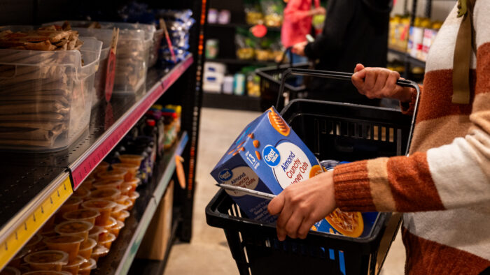 A person at a food band placing items in a basket.