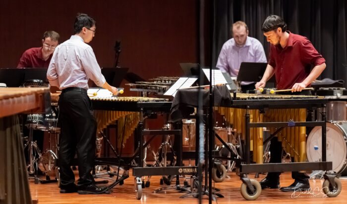Four members of a percussion ensemble performing in a concert.