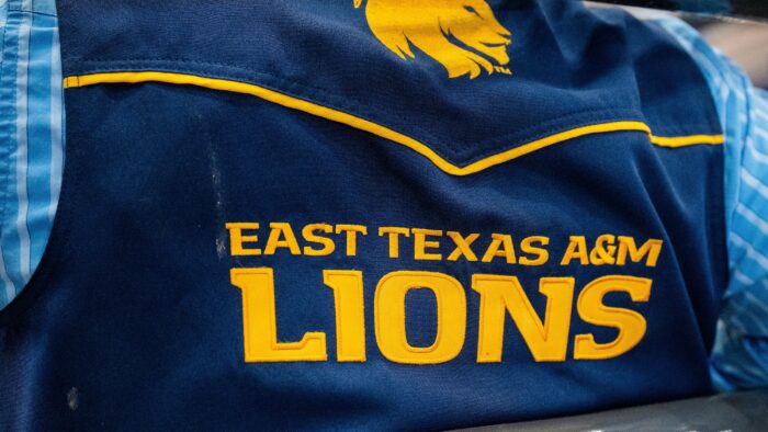 A closeup photo of a rodeo competitor wearing a vest with the logo of East Texas A&M University.