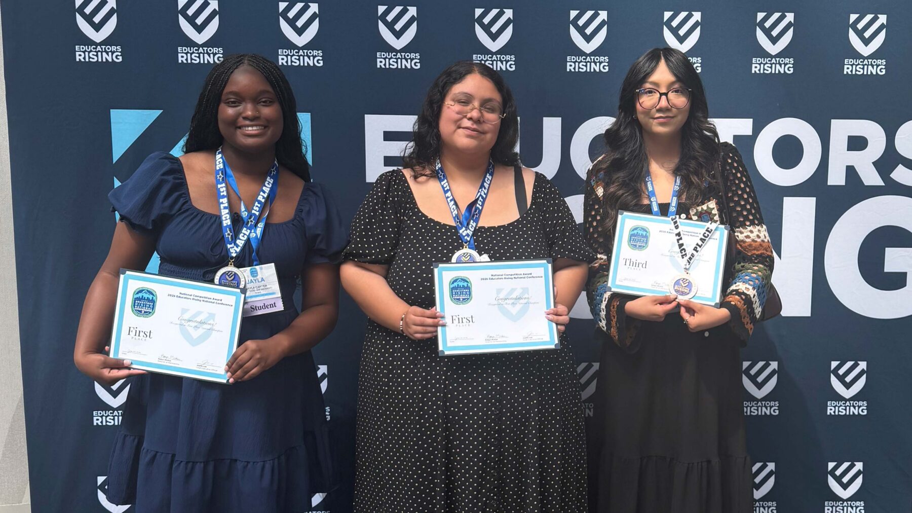 Three women stand holding certificates.