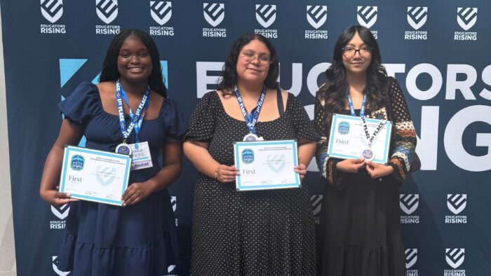 Three women stand holding certificates.