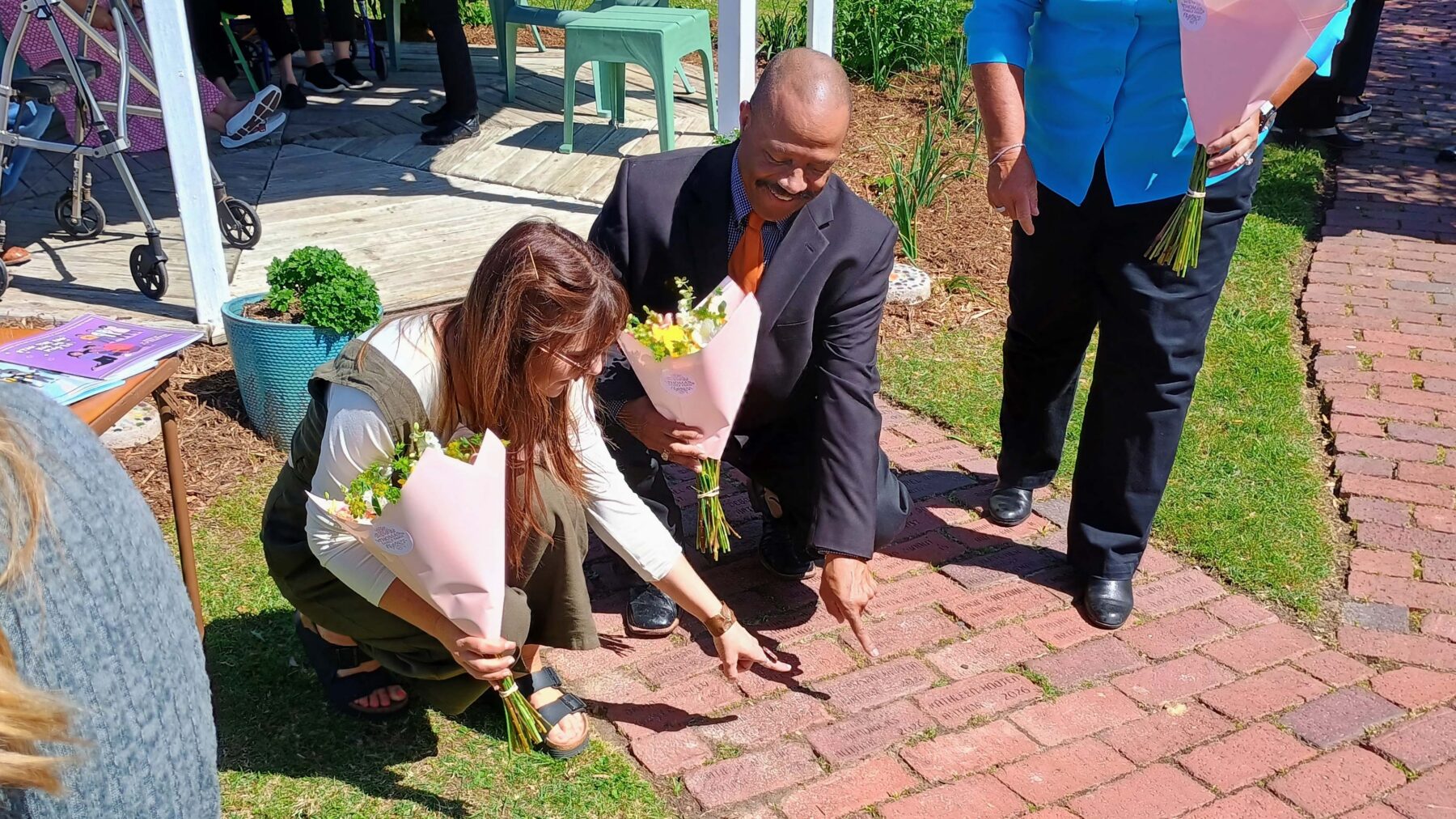 Two people squatting down pointing at a brick pathway.