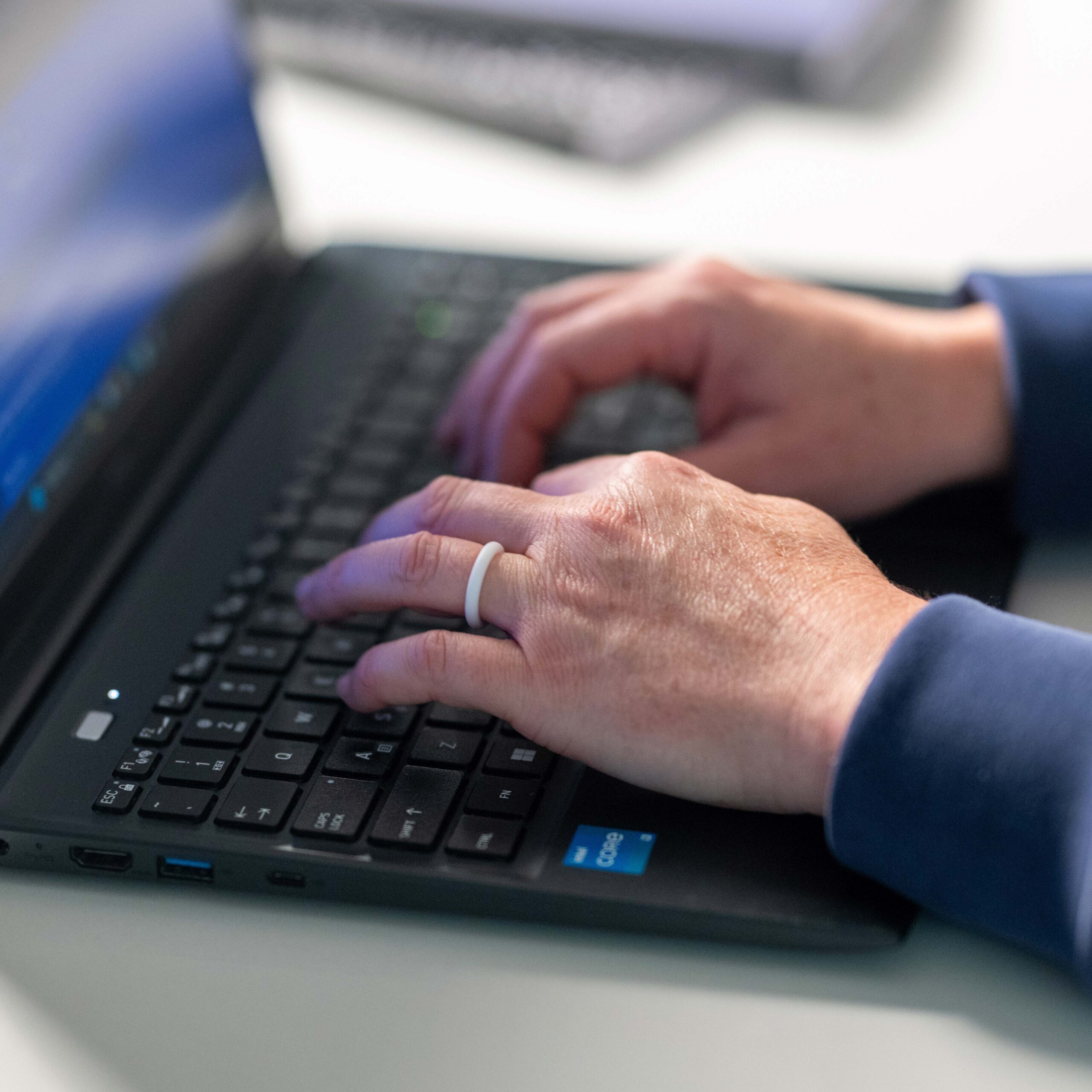 Hands typing on a laptop keyboard.