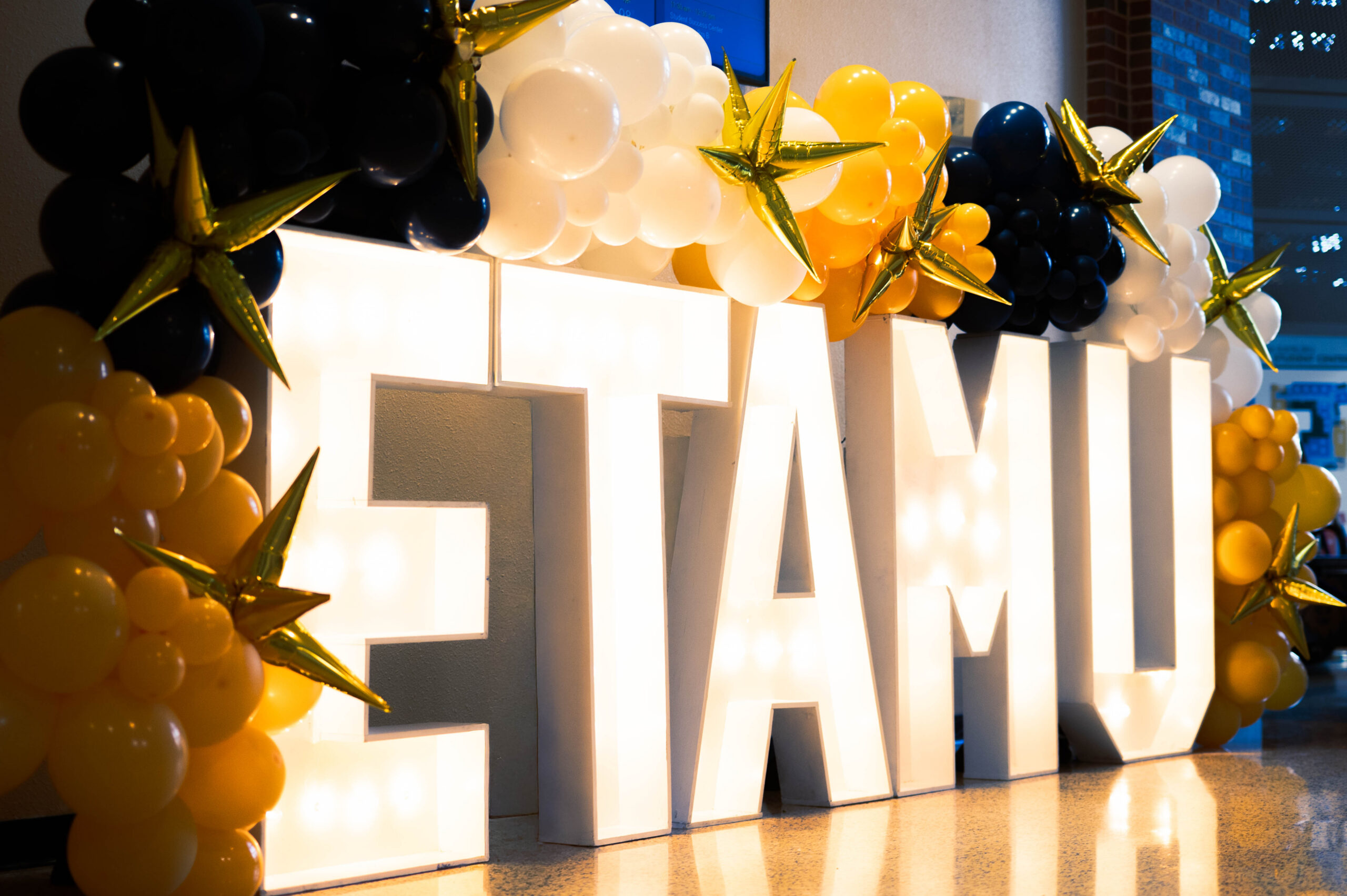 Glowing letters E.T.A.M.U. on a stage