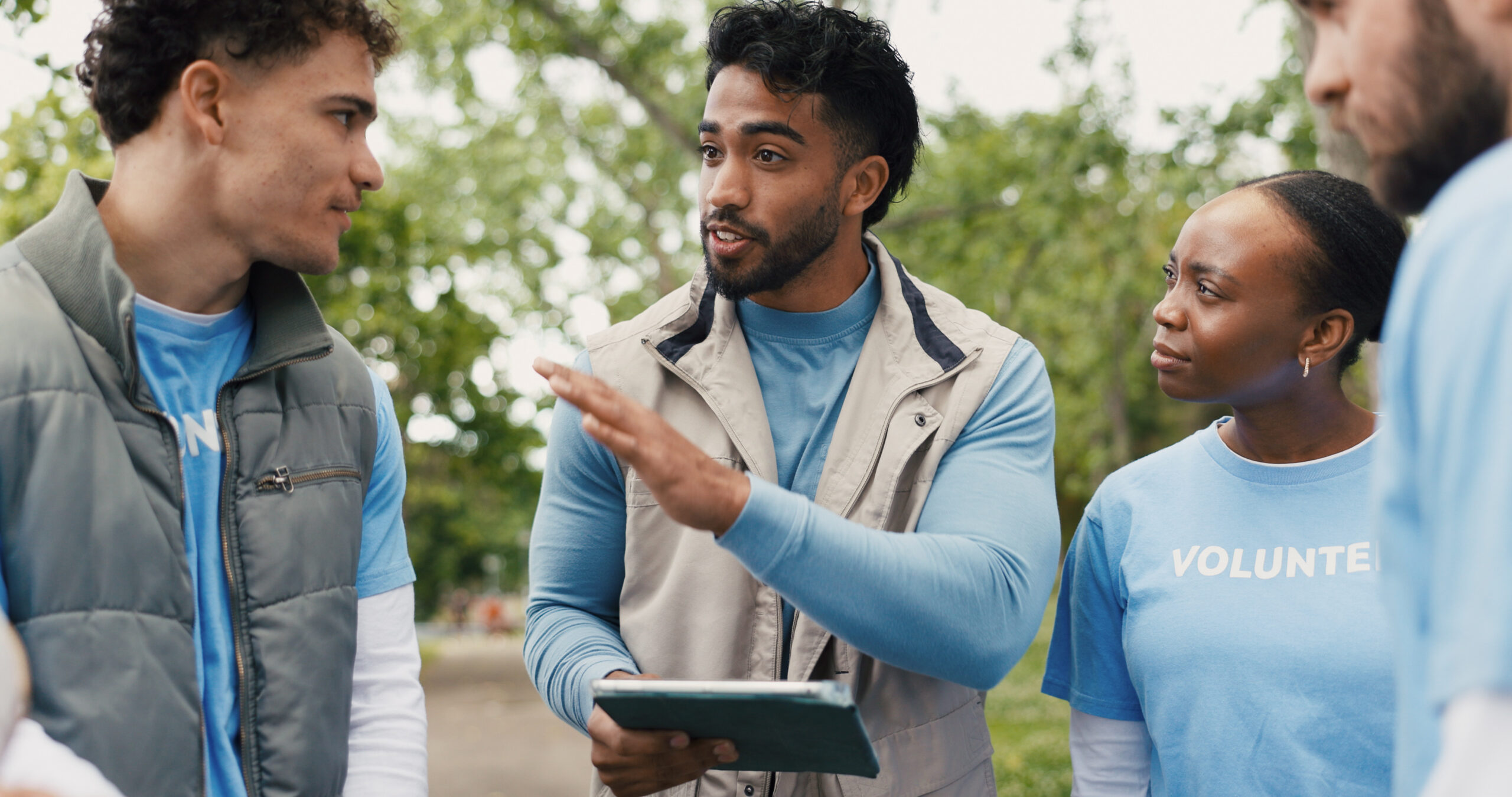 Four people stand outside wearing volunteer shirts