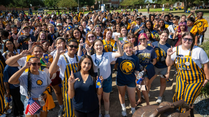 A large crowd of people gathered on a college campus for a group photo.