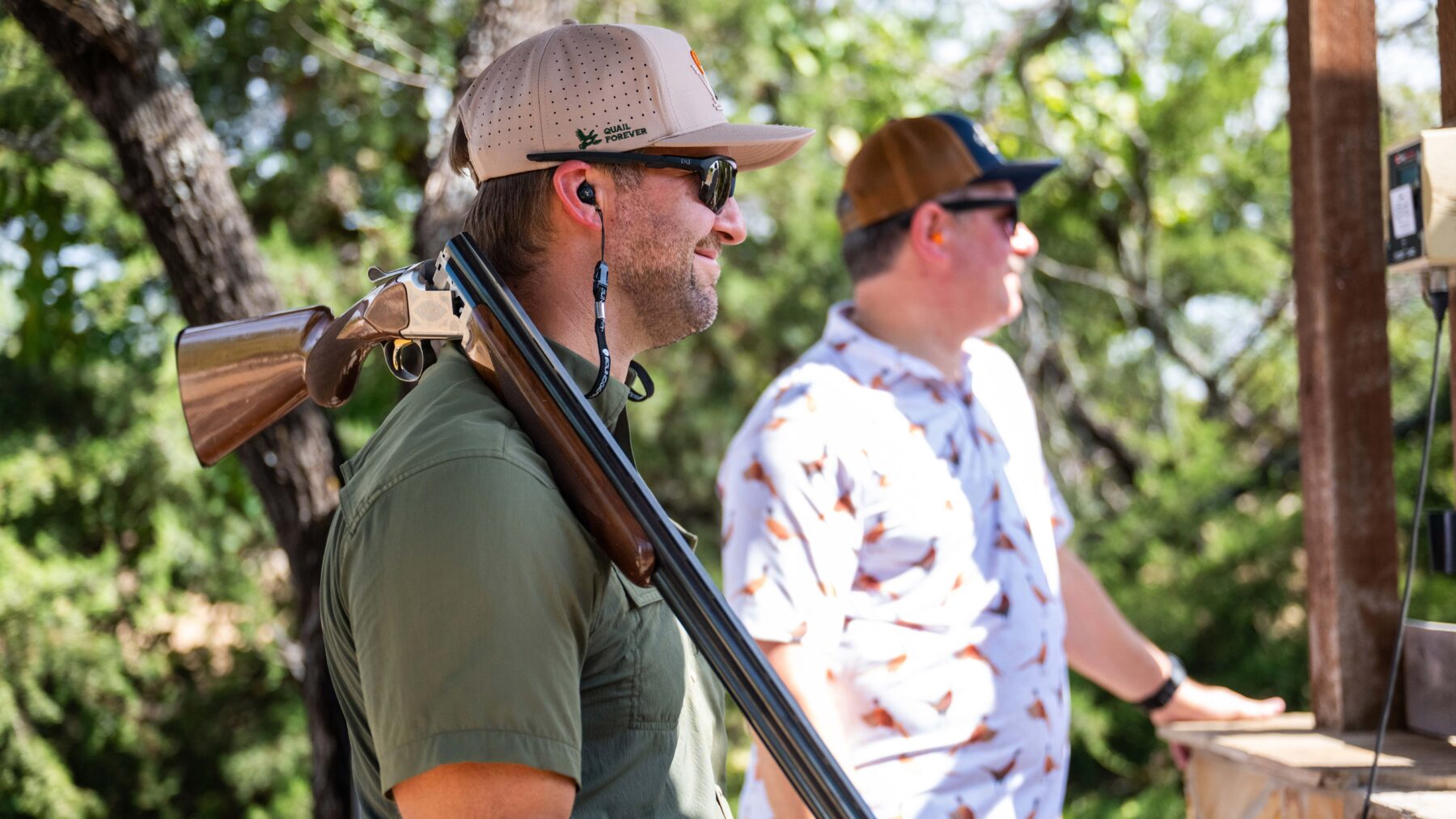 Man stands with double barrel shotgun over shoulder.