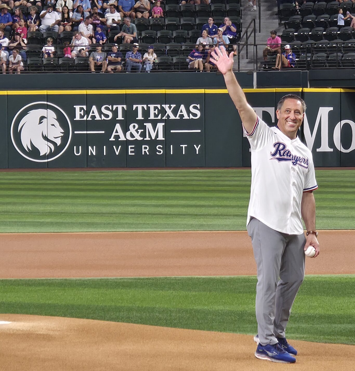 A person in a baseball jersey waving to a crowd at a baseball game.