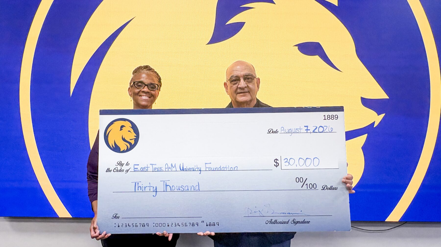 Two people holding a large ceremonial cheque.