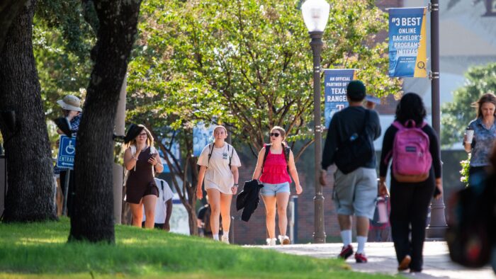 College students walking on a sidewalk on a college campus.