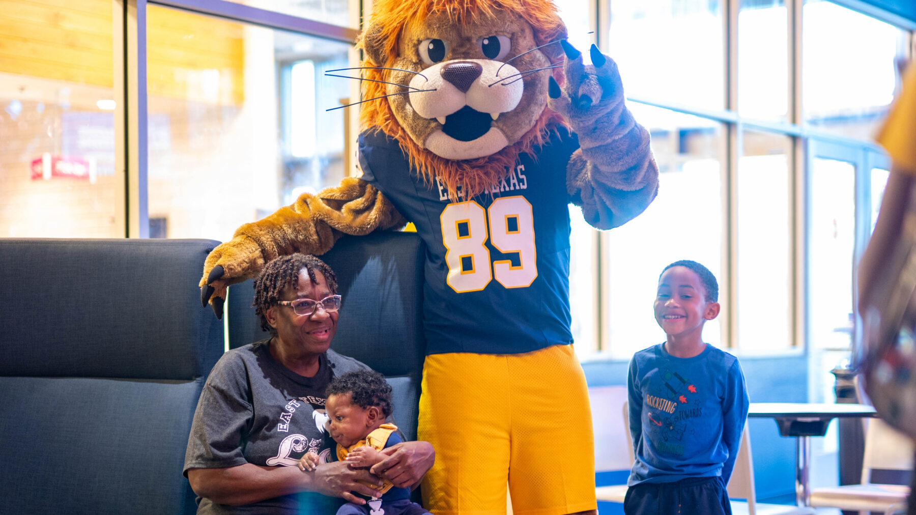 A person in a Lion mascot costume with a mother and two children.
