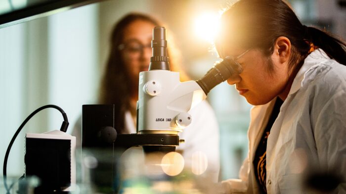Woman looking into a microscope.